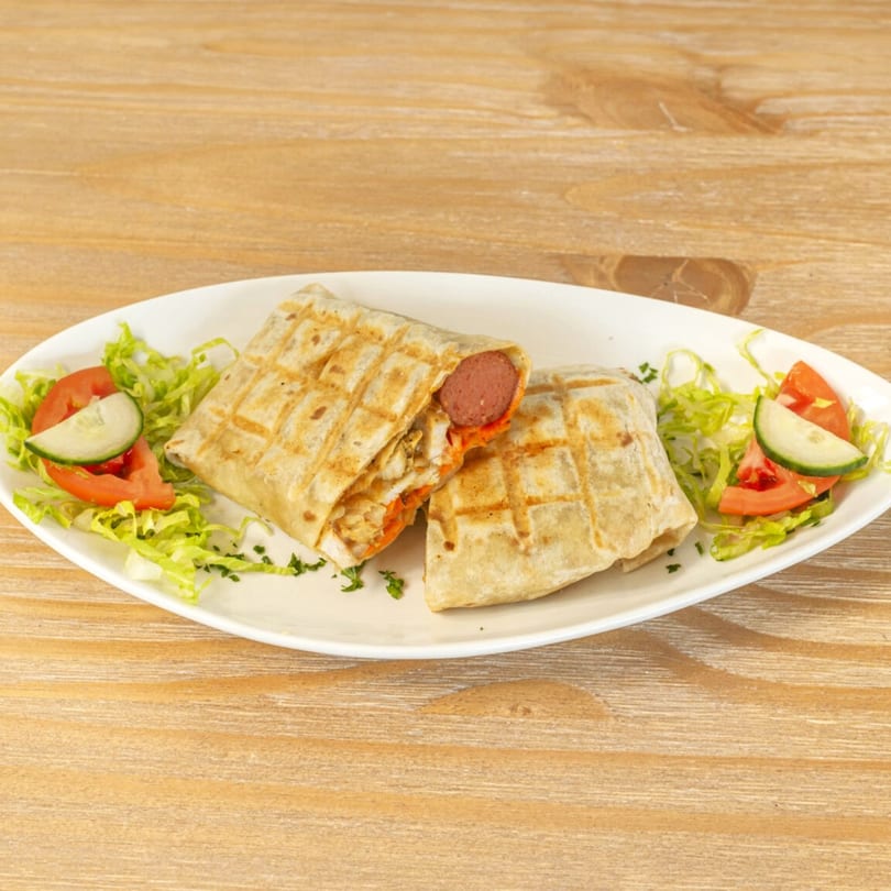 Two grilled wraps, one with a visible sausage, served with lettuce, tomato, and cucumber.