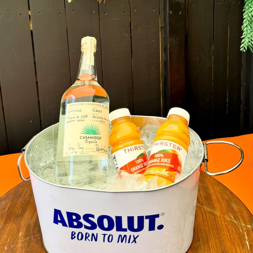 Casamigos tequila bottle and two orange juice bottles in an Absolut ice bucket.